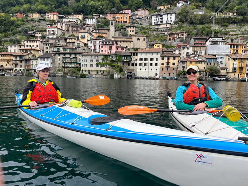 Gandria, Switzerland pictured behind kayakers on Lake Lugano. 