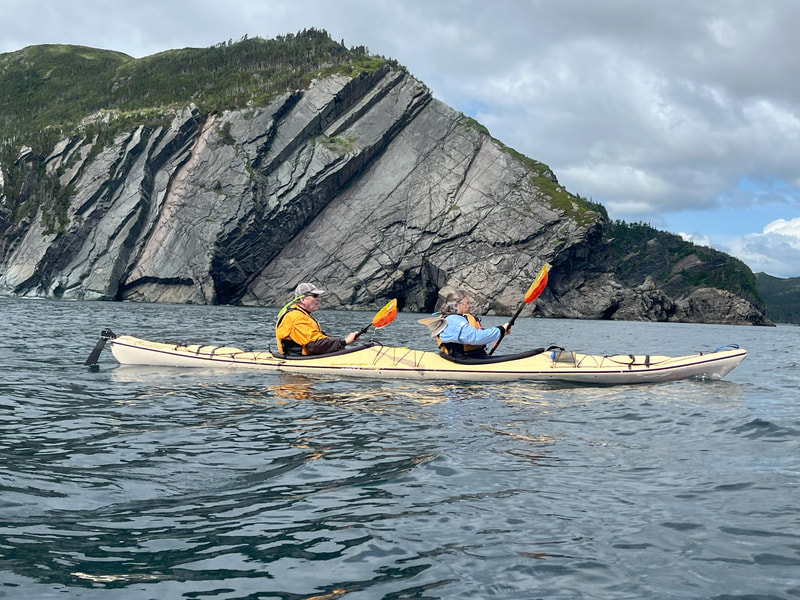 Kayak going past rocky cliff