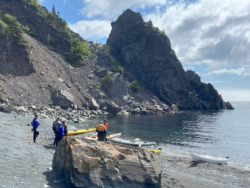 Kayaks on a rocky beach surrounded by cliffs