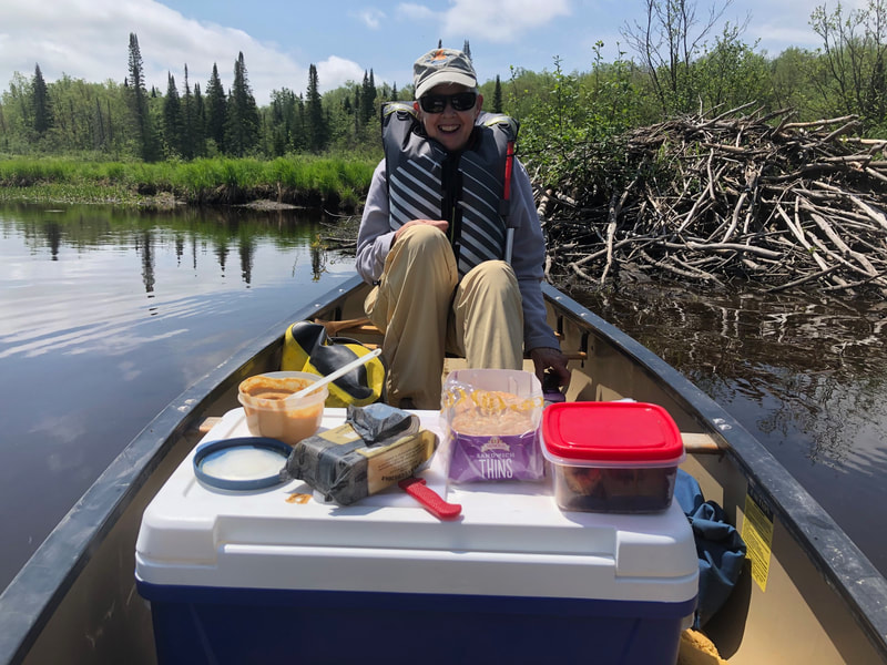 Lunch in a canoe with a beaver house in the background